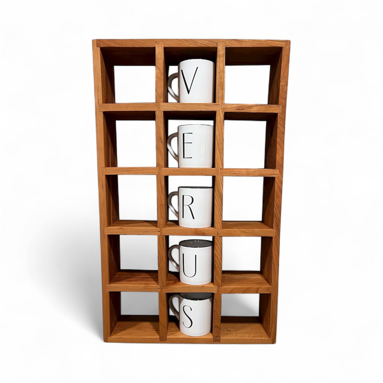 Wooden cube shelf with five white mugs labeled with letters on a white background