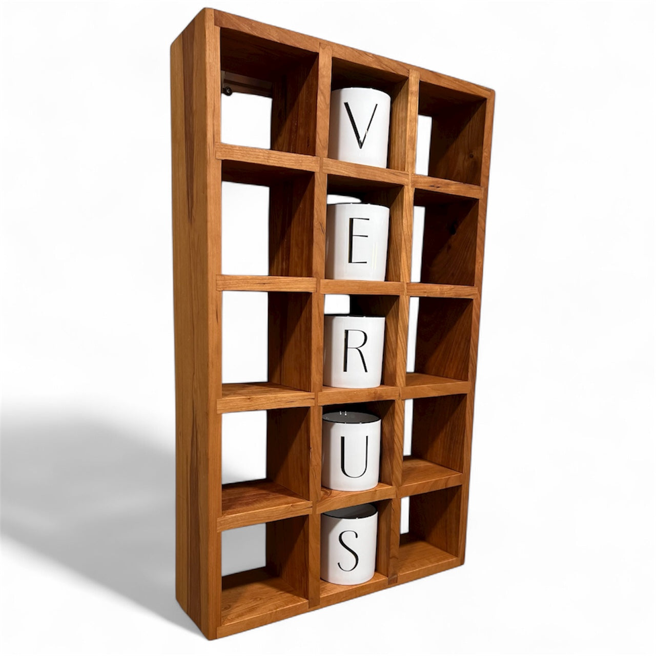 Wooden bookshelf with square compartments holding white containers with letters.