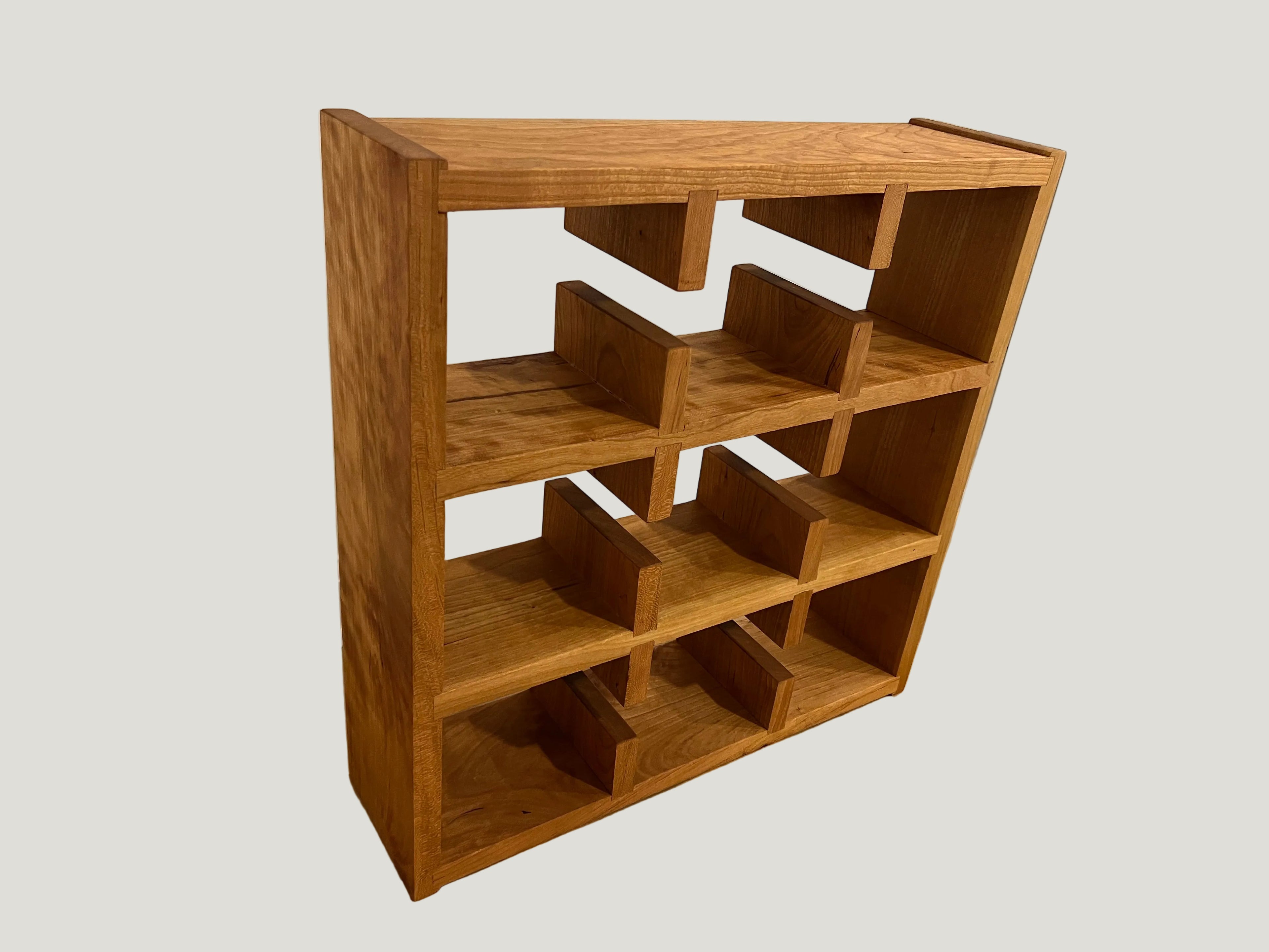 Wooden shelf with geometric design on a plain floor.