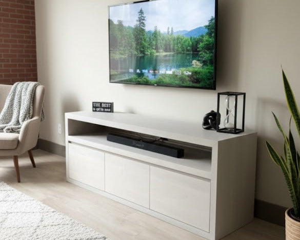 Modern living room with a television mounted on the wall above a white entertainment console.